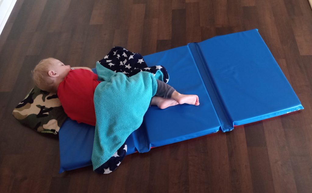 kid sleeping on a mat in a sparse room